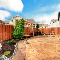 Fenced backyard with concrete tile floor deck and decorated flower bed