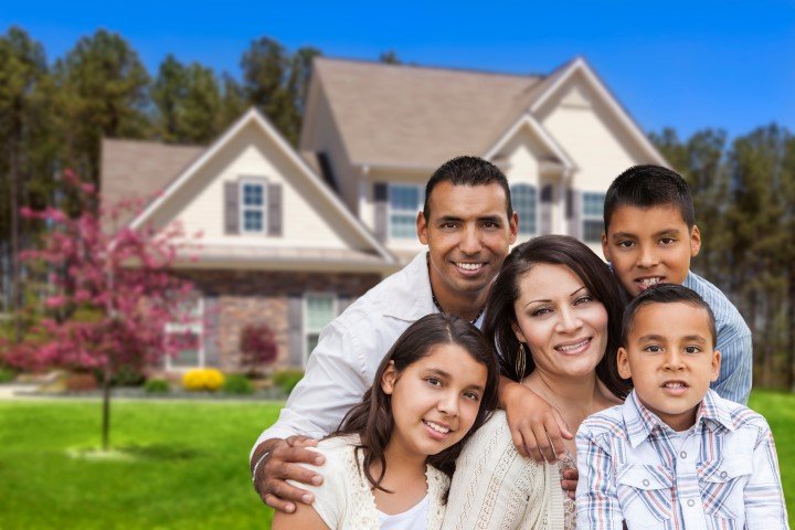 Happy Hispanic Family Portrait in Front of Beautiful House.