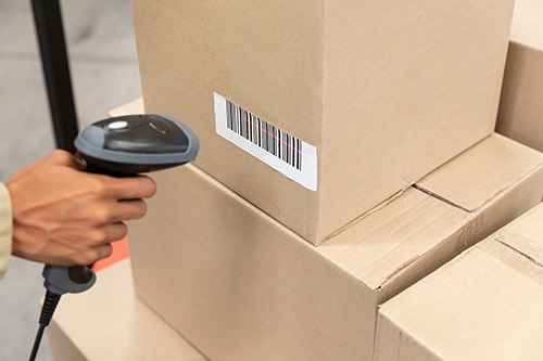 Close-up of female worker scanning package with barcode scanner in warehouse. This is a freight transportation and distribution warehouse. Industrial and industrial workers concept